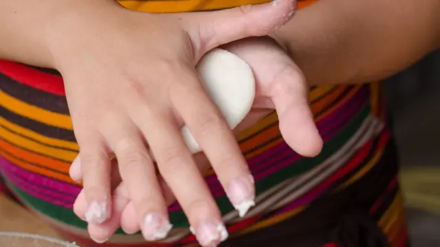 Una mujer amasada una harina de maíz para hacer arepas.