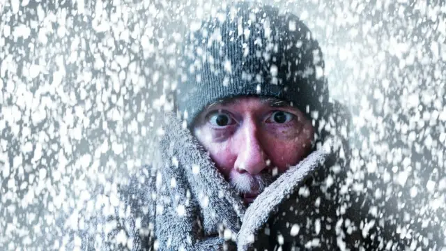 Una persona abrigada con nieve a su alrededor.