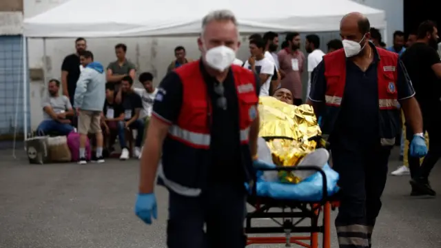 希腊卡拉马塔港救护员将一名获救的船民以担架抬走（16/6/2023）