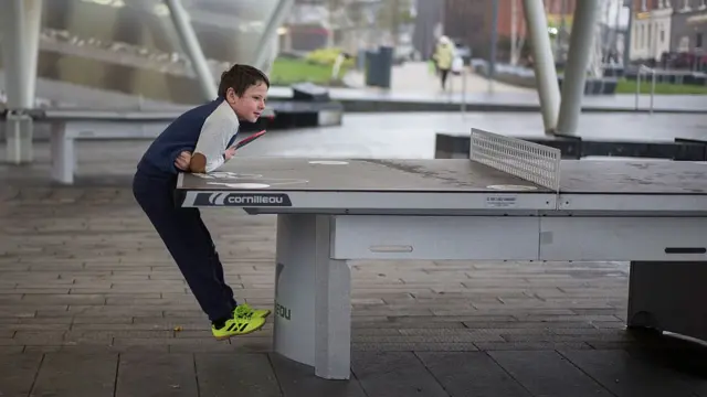 хлопчик висить на столі для настільного тенісу