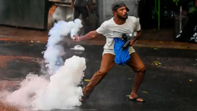 A demonstrator throws back a tear gas canister fired by police to disperse students taking part in an anti-government protest demanding the resignation of Sri Lanka's President Gotabaya Rajapaksa over the country's crippling economic crisis, in Colombo on 29 May, 2022.