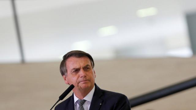 Bolsonaro olha para o lado em frente a microfone
