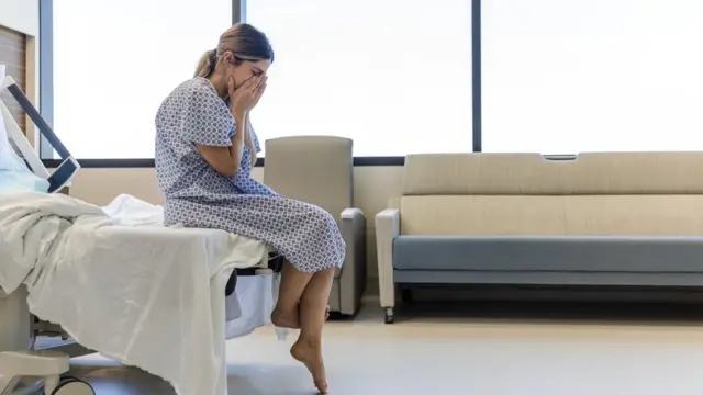 Une femme assise sur un lit dans une clinique