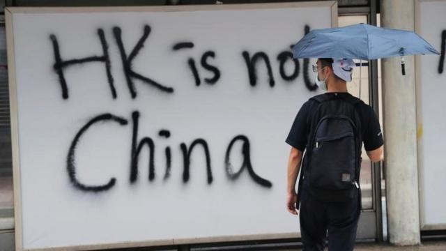 Protestor stands in front of graffiti