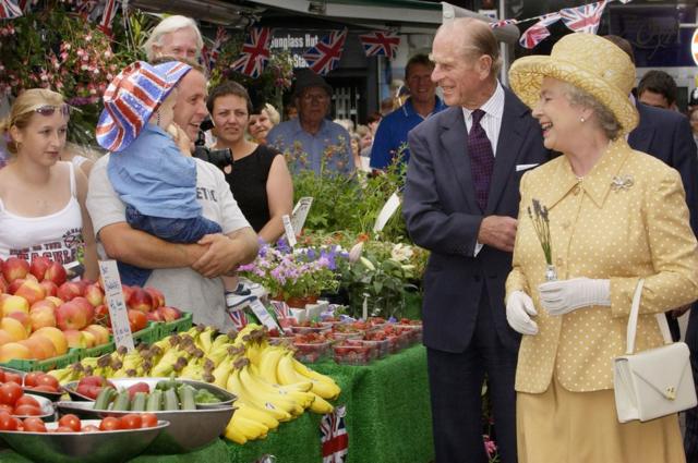 A Rainha Elizabeth II (à direita) e o Duque de Edimburgo (centro ) visitam as bancas do mercado no centro da cidade de Kingston, durante a visita do Jubileu de Ouro da Rainha ao oeste de Londres
