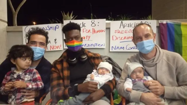 Phillip Lühl, Guillermo Delgado y un amigo de la pareja cargando a las gemelas, Paula and Maya, y a Yona.