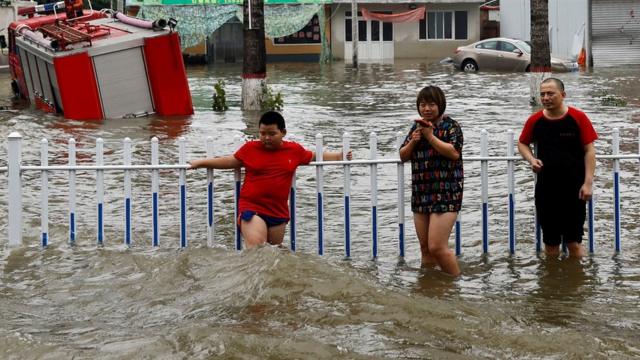 People stand by a rail amid floodwaters after the rains and floods brought by remnants of Typhoon Doksuri, in Zhuozhou, Hebei province, China August 3, 2023.