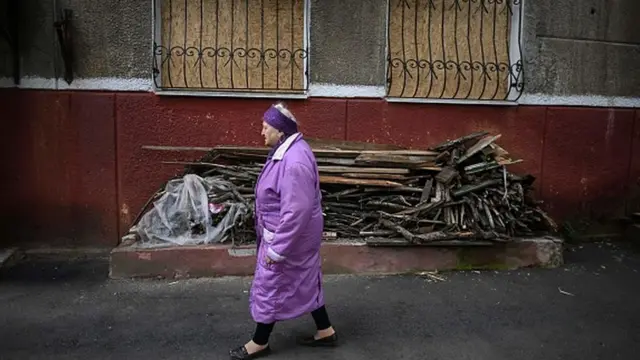 Жінка біля пошкодженого будинку