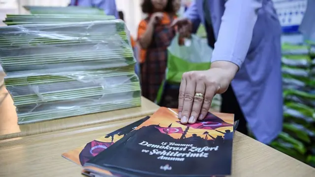 Öğretmeni çocuğa 15 Temmuz broşürü veriyor.