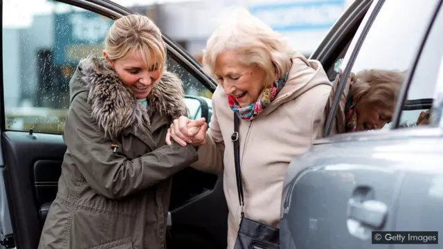 Mulher ajudando idosa a sair do carro