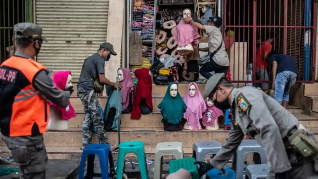 Petugas Satpol PP membantu pedagang mengemas barang dagangnya saat berpatroli di kawasan Pasar Tanah Abang, Jakarta, Sabtu (23/05)
