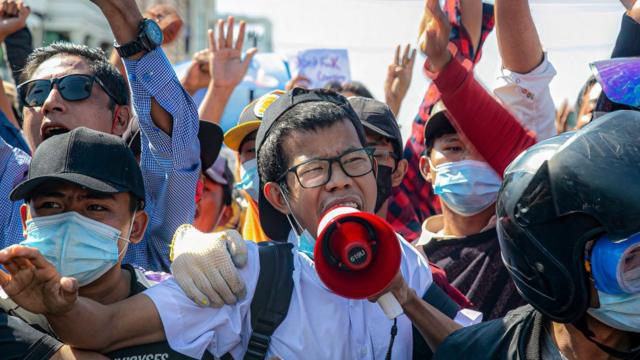 Protesters shout slogans through a megaphone at the junction
