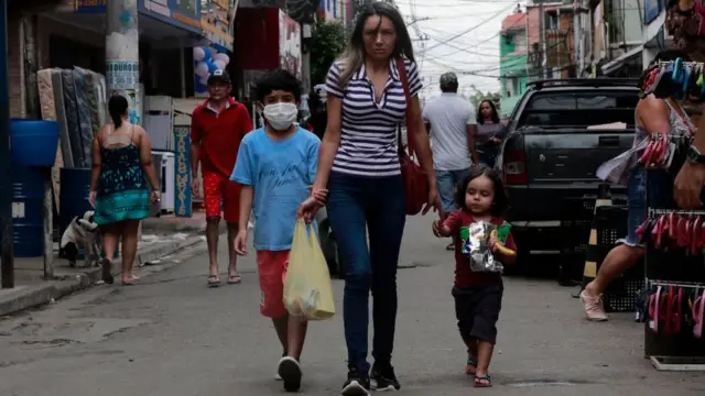 Una mujer camina con sus dos hijos