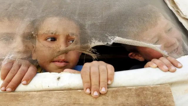 लेबानन में अपने टेंट से झांकते सीरियाई शरणार्थी बच्चे