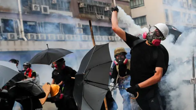A demonstrator throws back a tear gas canister as they clash with riot police during a protest in Hong Kong, China, August 24, 2019.