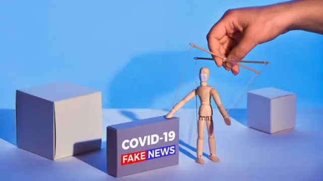 Ilustração gráfica mostra bonecosuper bet 365madeira controlado por mão, como um fantoche, ao ladosuper bet 365caixa que diz: 'Covid-19 Fake news'