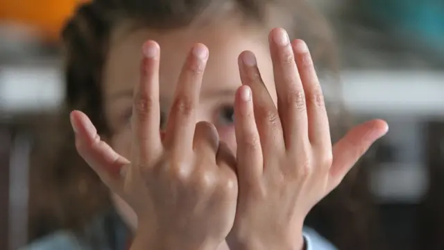 Бармоқлари билан саккизни кўрсатаётган бола