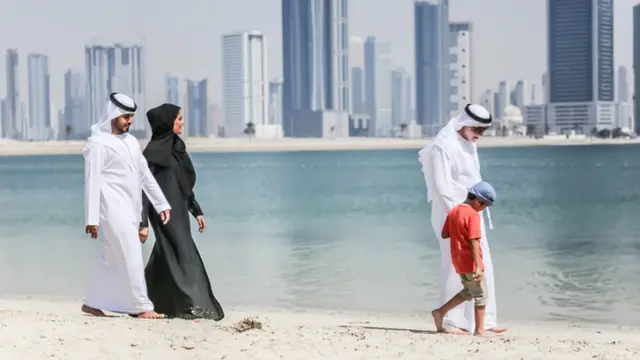 क़तर में पुरुष के साथ चलती महिला