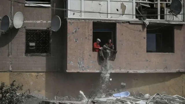 Dos hombres sacan escombros de su apartamento golpeado por la artillería rusa en Kramatorsk (Donetsk).