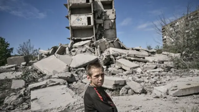 A young boy stands in front of a damaged building after a strike in Kramatorsk in the eastern Ukranian region of Donbas, on May 25, 2022.