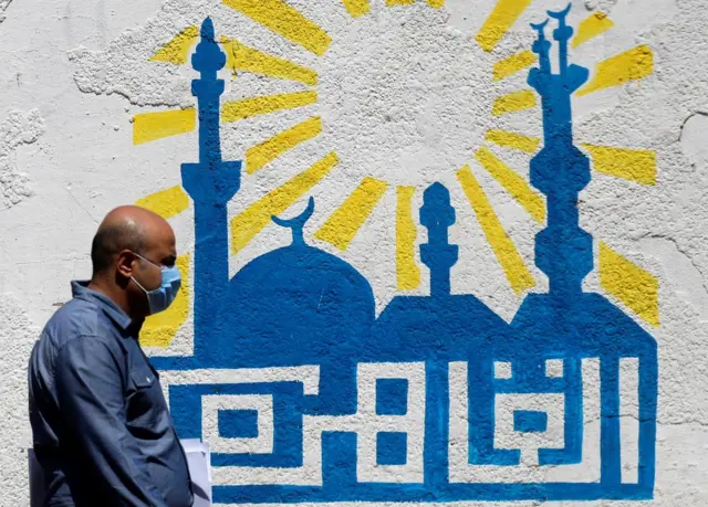 A man wearing a protective mask, amid concerns over the coronavirus, walks next to painted Arabic words reading "Cairo" in the city"s downtown, Egypt June 27, 2020.