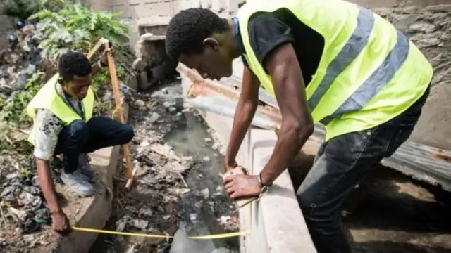 Des étudiants universitaires mesurent un canal de drainage