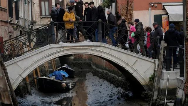 Turistas observan un canal casi seco.