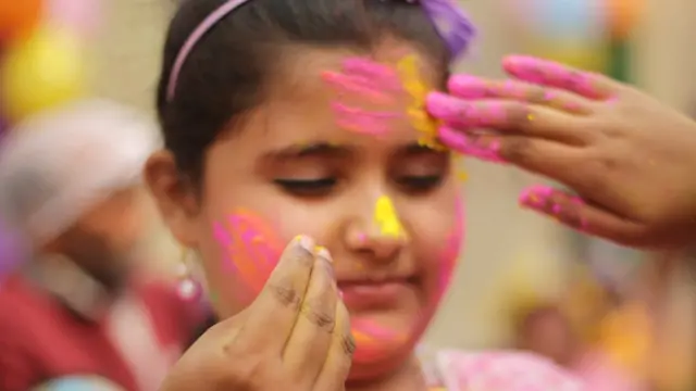 कोलकाता में मानसिक रूप से कमज़ोर बच्चों के एक स्कूल में अपने साथी को गुलाल लगाते बच्चे.