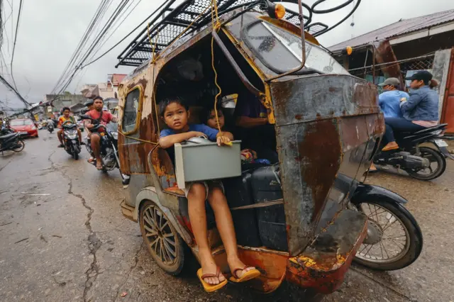 Una familia en motoneta huye del desastre