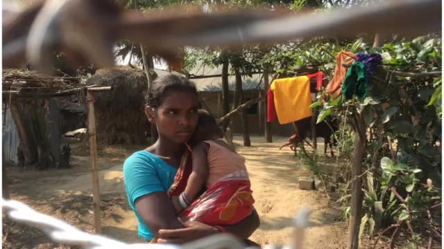 কিছুদিন আগেও সামনেই ছিল তার বাড়ি, এখন তার চারদিকে কাঁটাতারের বেড়া। সেদিকেই তাকিয়ে রয়েছেন এই সাঁওতাল নারী