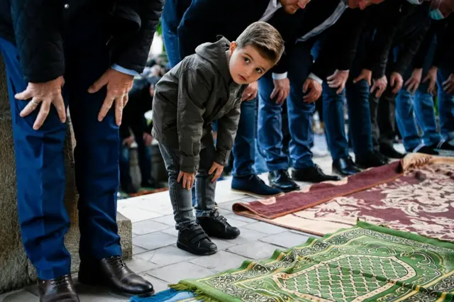 A young boy looks on as he takes part in Eid prayers in Pristina, Kosovo