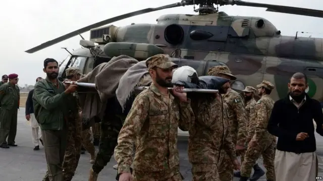 Pakistani soldiers walking with a stretcher in front of a helicopter carry an injured victim of a bomb blast in Parachinar, Peshawar, Pakistan, on 21 January 2017.