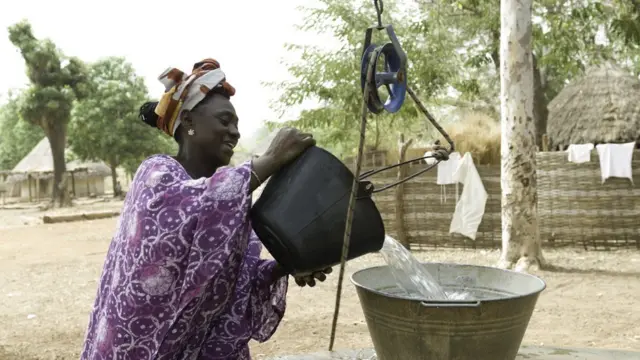 Une femmes Bassari avec foulard transportant de l'eau d'un puits.