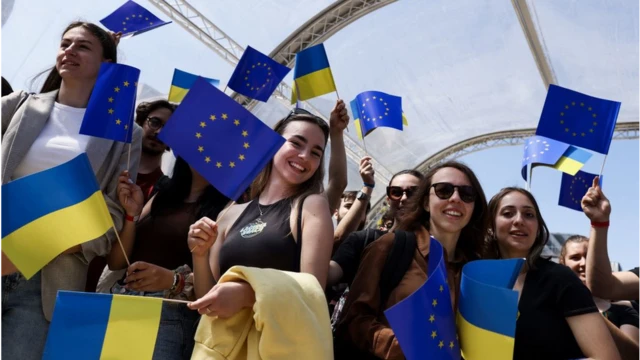 زوار من دول الاتحاد الأوروبي في بروكسل يلوحون بأعلام الاتحاد الأوروبي وأوكرانيا