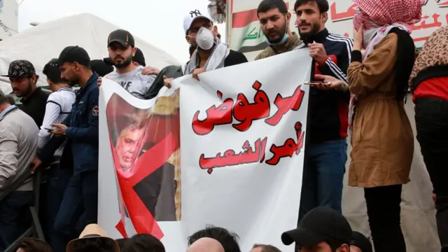 متظاهرون يحملون صورة لعلاوي مكتوب عليها "مرفوض بأمر الشعب"