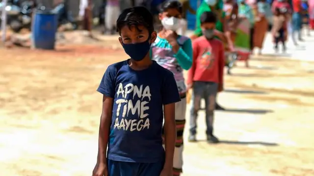 માસ્કર પહેરેલા બાળકો લાઇનમાં ઊભા છે