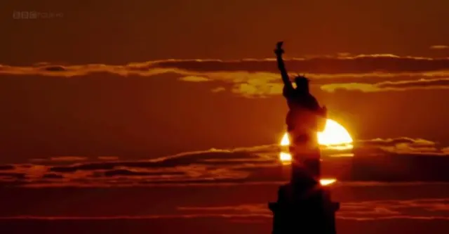 미국 뉴욕 자유의 여신상 조형물 뒤로 태양이 지고 있다