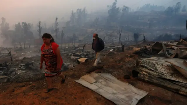 Gente camina sobre escombros.