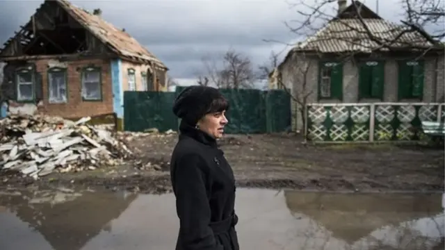 Жінка у зруйнованому війному селі
