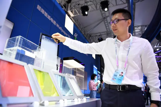 工作人员正在展示智能热致调光玻璃。它可以根据环境温度和太阳辐射强度变化自动调节状态，以进行遮阳和隔热。