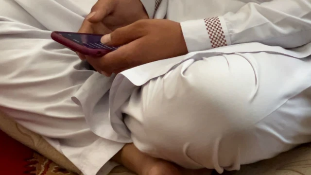 Mohammad seated on the floor scrolling through his phone