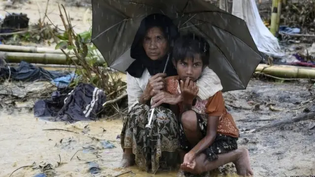 Rohingya refugees shelter under an umbrella during rain in Bangladesh"s Balukhali refugee camp.