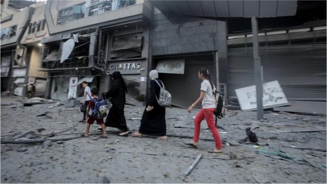 以色列加沙冲突：人们走过加沙受损的建筑