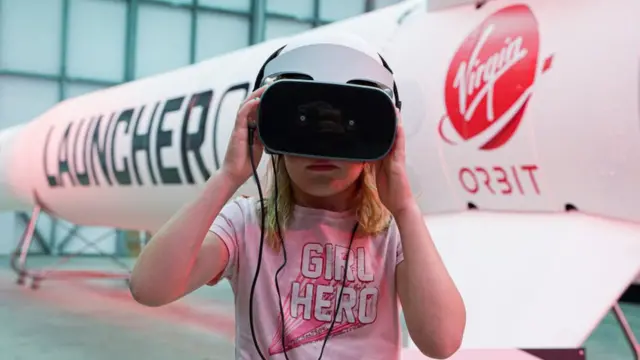 A girl uses a VR unit in front of the Virgin Orbit Launcher One rocket in Newquay, England.