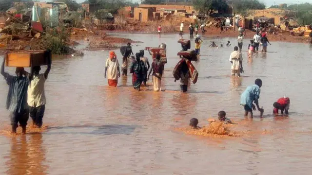 Residents of the city of Agadez, nothern Niger, walk in a flooded street on September 2, 2009 after heavy rains hit the country. Four people died and three were injured when a mud house collapsed in floods at Lazaret, a poor district of the Niger capital Niamey, private television channel Dounia reported late September 12, 2009