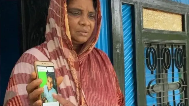 হাজীগঞ্জে সায়রা বেগম মোবাইল ফোনে তার নিহত সন্তানের ছবি দেখাচ্ছেন। তিনি বলেছেন, প্রশাসন ও আল্লাহর কাছে তিনি এর বিচার চান।