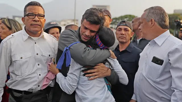 Leopoldo López aparece com uma fita azul no braço e abraçando uma mulher,banca baixa no aviatormeio a apoiadores