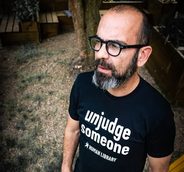 Ronni Abergel, fundador da Biblioteca Humana, com uma camisetaentender apostas esportivasque se lê "'Desjulgue alguém"