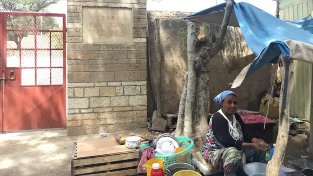 የአፍሪካ እና የብሪታንያ ወታደሮች መካነ መቃብብ በር ላይ አነስተኛ የንግድ ሥራ የምታከናውን ሴት