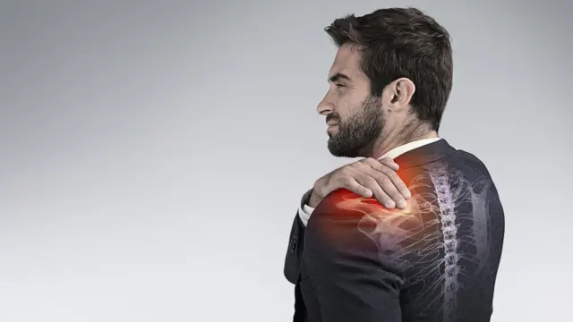 Hombre con traje y dolor en el hombro.